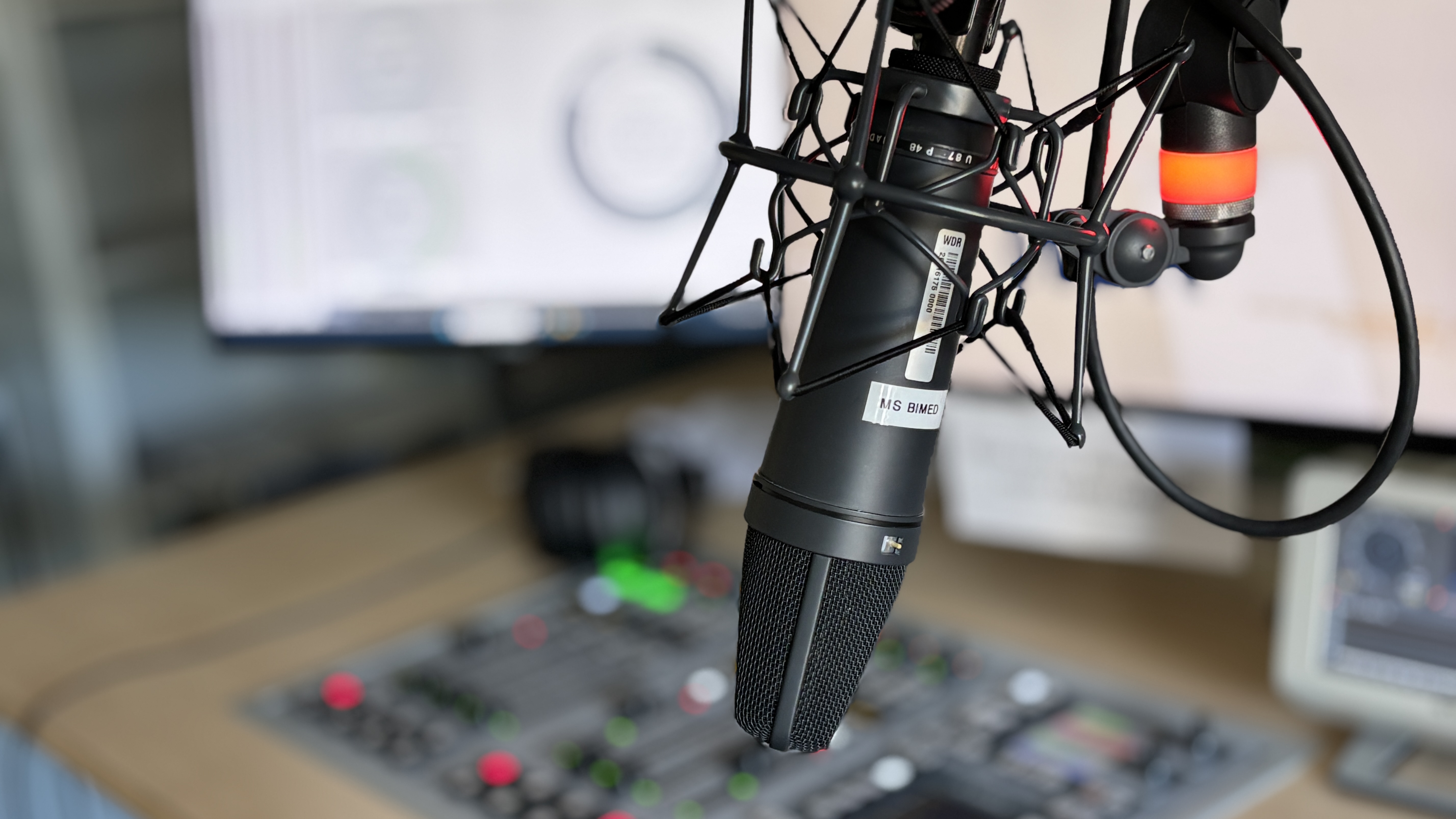 Ein Mikrofon über einem Mischpult in einem Hörfunk-Studio.